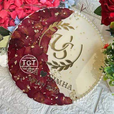 A beautiful 10-inch round resin plaque preserving red rose petals in a crescent moon shape. This piece features a custom couple logo, names, and wedding date in gold on a shimmery ivory base.