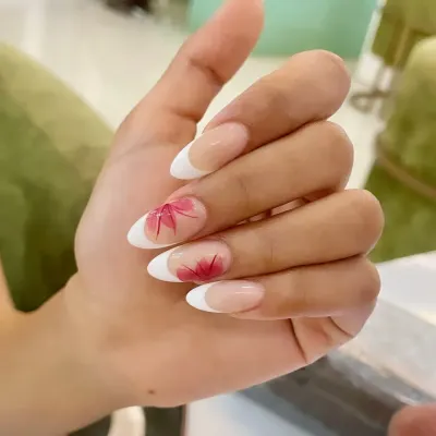 A beautiful example of our hand-painted floral art. This design features a classic French manicure on almond nails, with delicate red maple leaves painted on accent nails for an autumnal touch.