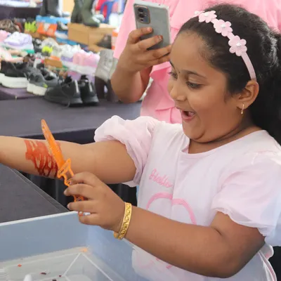 Shock, surprise, and a whole lot of laughter! This young actress is having a blast with her fake knife-through-the-arm effect. It's a perfect photo opportunity and a memorable party trick.