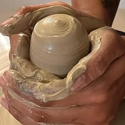 The quintessential moment of creation on the potter's wheel. This image captures the feeling of centering clay, the first step in transforming a simple lump of earth into a beautiful, functional vessel.