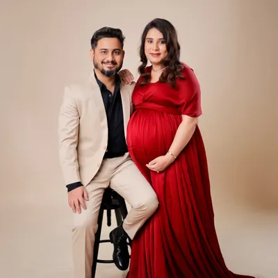A classic and formal couple's portrait. The combination of his sharp suit and her elegant red gown creates a sophisticated look against a clean studio backdrop.