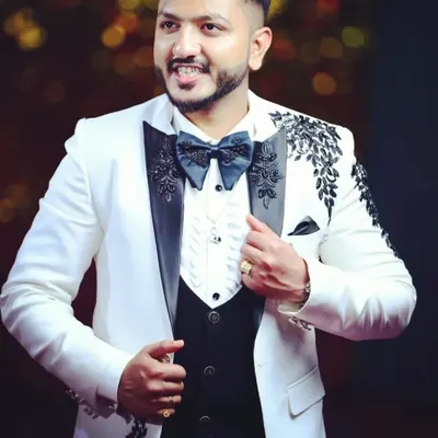 A client looking sharp in his custom white tuxedo with detailed black embroidery. We design event wear that ensures you stand out, with every element from the fabric to the fit tailored specifically for you.