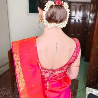 A back view of a classic South Indian bridal hairstyle. This features a neat, slick bun adorned with a traditional floral gajra, which looks incredibly elegant with a silk saree.