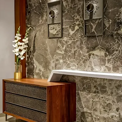 A close-up view of a luxury foyer design. We paired a dramatic, dark marble feature wall with a custom wooden console that has textured drawer fronts, creating a powerful first impression.