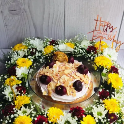 A full view of the Cherry Almond Tres Leches Floral Hamper. The cake is nestled in a bed of yellow, white, and red chrysanthemums, creating a beautiful and delicious birthday gift.