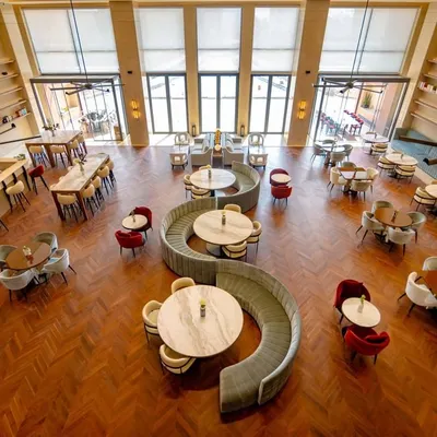 An overhead view of the Elevate Clubhouse showcases the strategic spatial planning that defines our work. Curvilinear sofas create intimate gathering spots within the larger, open-plan layout, while the rich wooden flooring adds warmth and sophistication to this central community space.