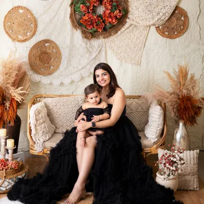 A beautiful mother and daughter portrait in matching black outfits. The boho-chic studio setup adds a warm and stylish touch.