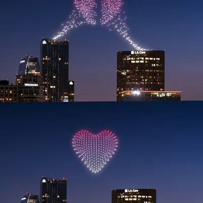 My flexible technology allows me to operate where others cannot. Here you can see my drones taking off from two separate building rooftops to form a single, unified heart shape, a testament to my advanced planning and execution capabilities.