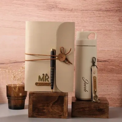 This beautifully styled gift set features a personalized cream-colored diary with a pen and a matching insulated tumbler engraved with the name "Jacob." It's a thoughtful and practical gift for any occasion.