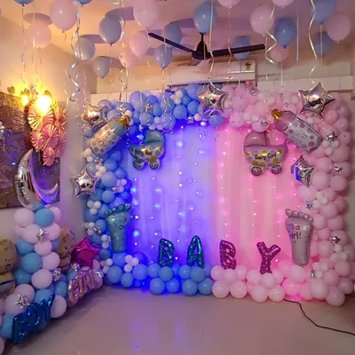 A full-room baby shower decoration with a "Boy or Girl" theme. The setup is split into blue and pink sections, each with its own balloon garland, shimmer curtain, and themed foil balloons like baby carriages and footprints.