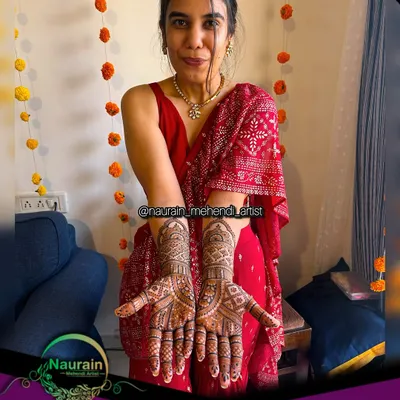 A happy bride in red, showcasing her intricate bridal mehendi. Her smile says it all.