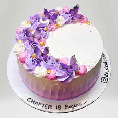 An elegant whipped cream cake with purple ombre frosting and delicate butterflies. The message "Chapter 18 Begins" marks a special milestone with style.