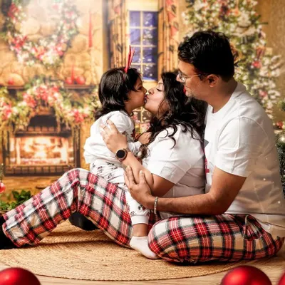 A sweet family kiss in front of our cozy Christmas fireplace backdrop. Our holiday mini sessions are perfect for creating photos for your annual cards and making lasting memories.
