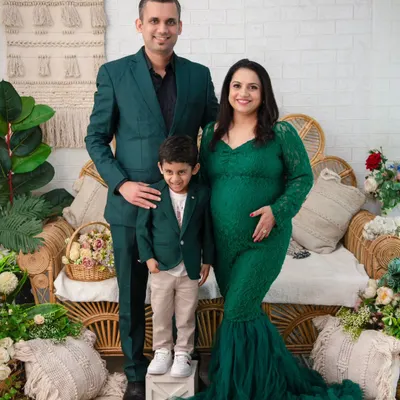 A picture-perfect family portrait. The coordinating green outfits, the proud parents, and the excited big brother create a harmonious and heartwarming image. This is a beautiful way to document the family just before it grows.