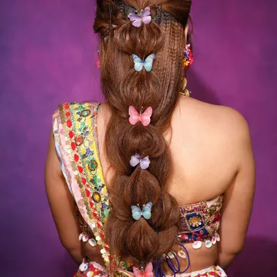 A whimsical and modern bubble braid hairstyle, adorned with colorful butterfly clips. This is a perfect look for a fun Mehendi or Sangeet function.