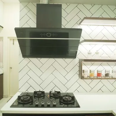 This kitchen features a stunning white herringbone tile backsplash that adds texture and a timeless pattern. The design is complemented by open wooden shelves with integrated LED lighting for a warm, ambient glow.