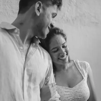A soft and intimate black and white portrait. The genuine smiles and gentle embrace convey a deep sense of comfort and affection, creating a timeless and emotional image.