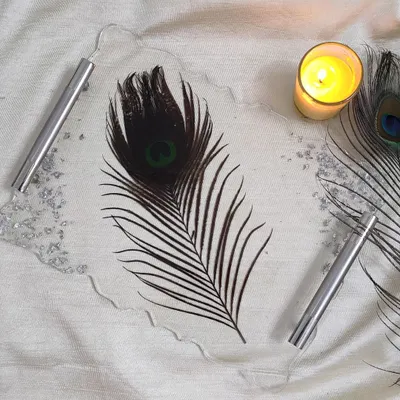 This custom tray features a single, striking peacock feather preserved in clear resin. The silver handles and flakes add a modern touch to this nature-inspired piece.