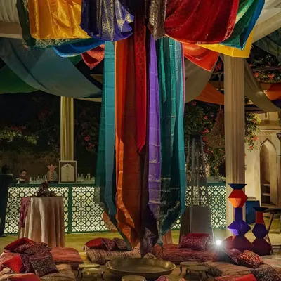 We transformed this space into a vibrant Moroccan souk, complete with low seating on colorful cushions and rich textiles draped from a central column. This setup was designed to encourage a relaxed and communal atmosphere.