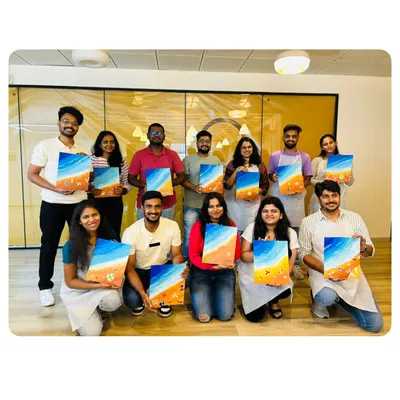 A successful corporate art workshop. The whole team is proudly holding up the beach-themed canvases they painted. It's a fantastic way to foster collaboration and boost morale.