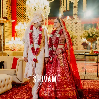A classic wedding portrait at the ITC Grand Bharat, where the couple's regal red and white attire stands out against the opulent decor.