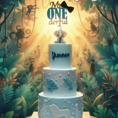 A "ONEderful" jungle-themed cake for a first birthday. This three-tiered creation features silhouettes of jungle animals and is topped with a cute fondant elephant.
