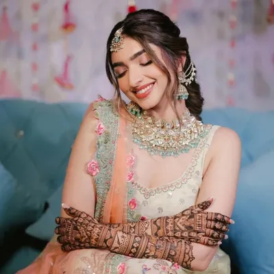 A stunning bride admiring her intricate mehndi. The design covers her arms completely, creating a beautiful and traditional look.