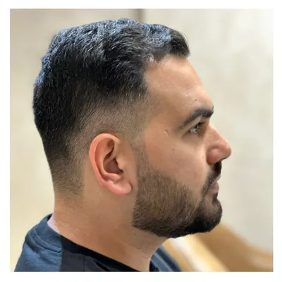 A close-up of a perfect skin fade. This image showcases the precision and skill required for a seamless blend, paired with a sharp beard lineup.