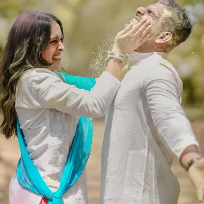 A moment of pure, uninhibited fun during a Holi-themed pre-wedding shoot, as she playfully smears color on his face.