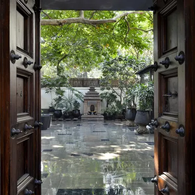 The entrance to our Golf Links Courtyard Home, framed by antique Chettinad doors. This view opens into the central courtyard, a tranquil space that serves as the heart of the home, connecting the various living areas.