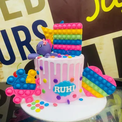 A vibrant 3kg Pop It theme cake, featuring edible, rainbow-colored Pop It toys and a fun drip effect.