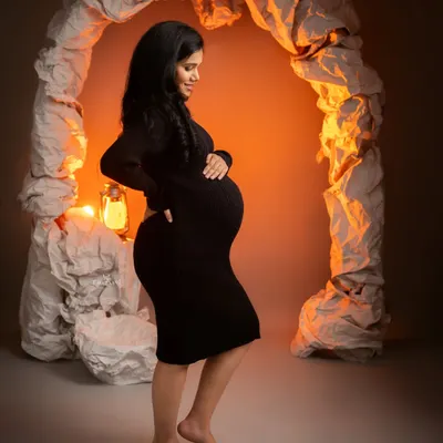 A simple and elegant silhouette against a warmly lit, textured archway. This shot beautifully highlights the baby bump in a minimalist and modern style.