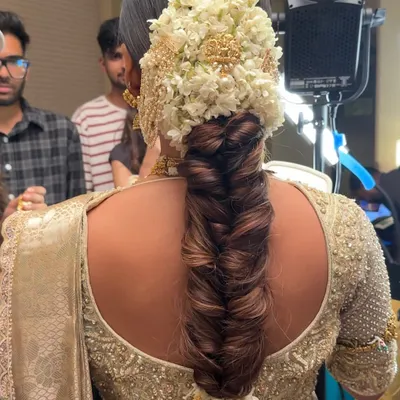 A behind the scenes look at the stunning South Indian bridal braid, showing the intricate fishtail plait before all the floral arrangements are added. This highlights the foundational skill required for such a detailed look.