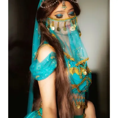 A full view of the Princess Jasmine cosplay. The makeup, featuring shimmering blue eyeshadow and winged liner, is paired with the character's signature costume and accessories for a complete transformation.