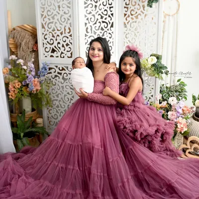 A picture of pure elegance with mom, big sister, and the new baby in matching ruffled gowns. This portrait showcases the beautiful bond between the leading ladies of the family in our floral studio setup.