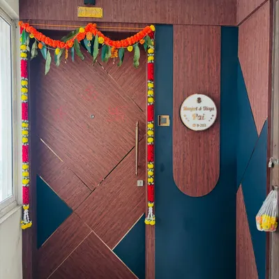 A modern main door with a geometric pattern and a two-tone wood and dark blue finish. The custom round nameplate adds a personalized and welcoming touch.