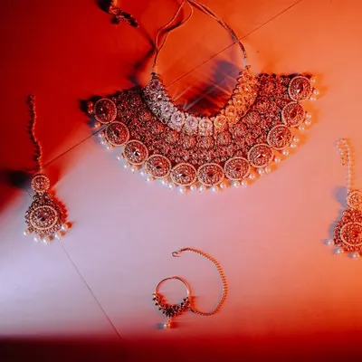 A beautifully styled shot of the bride's wedding jewelry. Capturing these details, like the necklace, earrings, and nath, is essential to telling the complete story of her bridal look.