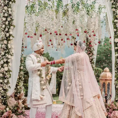 The pivotal Varmala moment, framed by a stunning floral arch at this beautiful outdoor wedding. This is where two worlds officially meet, and I capture it with all the grandeur it deserves.
