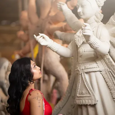 A creative shot from a Durga Puja themed shoot. The makeup is soft yet defined, with an emphasis on the eyes looking towards the divine idol, creating a narrative of devotion and grace.