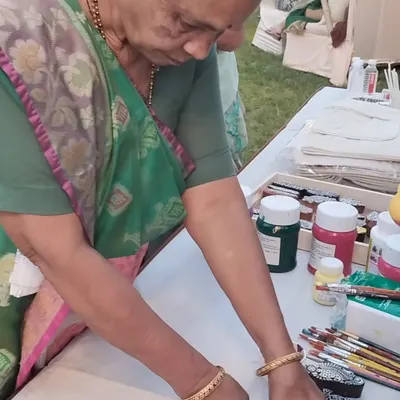 An elderly guest at a pre-wedding event carefully uses a stamp to add a design to a tote bag. Our art corners are designed to be accessible and enjoyable for guests of every generation, adding a unique touch to any celebration.