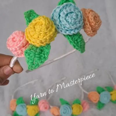A close-up of my rainbow floral headband. It features a bouquet of roses in different pastel colors with green leaves, all attached to a comfortable, satin-wrapped band.