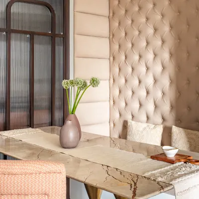 Luxury meets comfort in this elegant dining nook. A plush, tufted banquette provides cozy seating, while the marble-topped table with its sculptural wooden base adds a touch of modern sophistication.