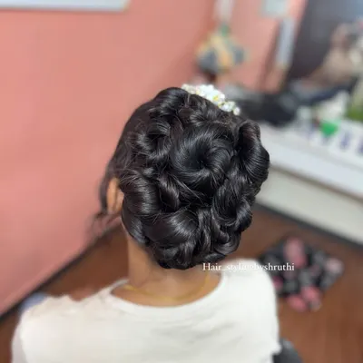 An intricate updo featuring multiple sculpted rose shapes, creating a stunning floral bouquet effect with the hair. This is a highly skilled and artistic style for a bride.