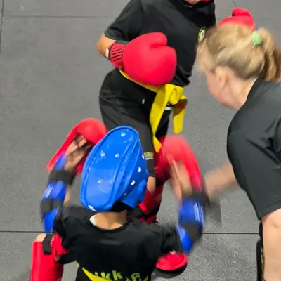 Learning to spar can feel scary, but we break it down every step of the way. Here, our coach guides young students, ensuring they learn at their own pace in a safe environment.