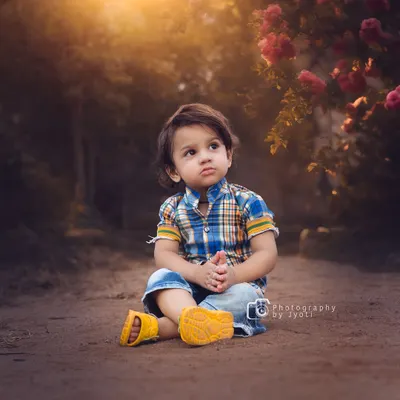 A thoughtful portrait of a young boy sitting on a rustic path, with the warm glow of the setting sun creating a beautiful, soft light. Outdoor sessions are perfect for capturing these serene moments.