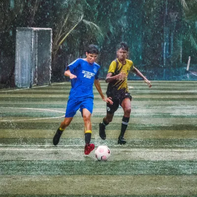 Rain or shine, the game goes on. An U-16 player skillfully dribbles the ball down a wet turf during the Independence Cup, showing determination against a defender.