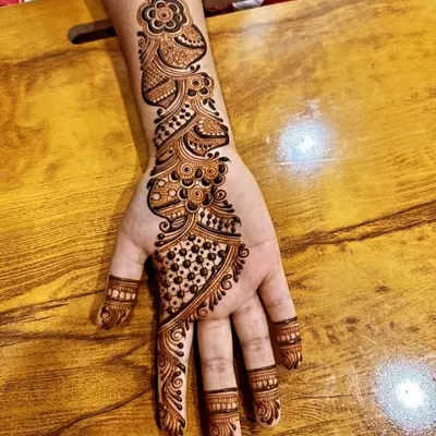 A classic Arabic mehandi design on the back of the hand. This style features a flowing vine of flowers and paisleys that runs from the index finger up the arm.