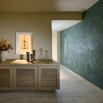 In this Delhi home, we used a deep teal lime plaster to create a feature wall embossed with a 'Tree of Life' motif. This artistic element greets you at the entrance, setting a tone of gentle harmony that flows through the rest of the living spaces.