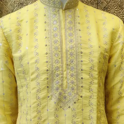 A vibrant yellow kurta, perfect for a Haldi ceremony. This piece features delicate silver embroidery around the neckline and placket, adding a touch of festive elegance.