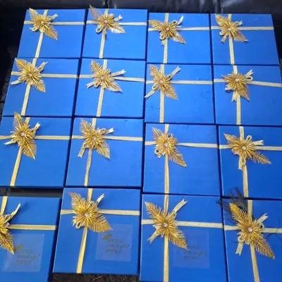A large order of customized return hampers for a first birthday party. The royal blue boxes with golden ribbons add a touch of elegance to the celebration.